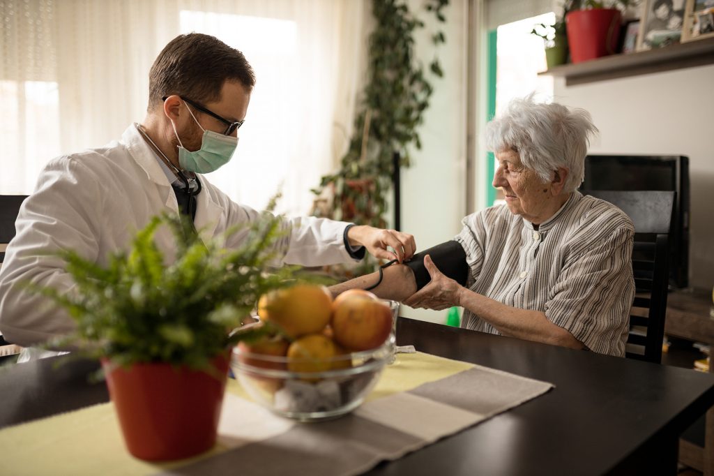 Doctor making a home-based primary care visit house call to an elderly patient